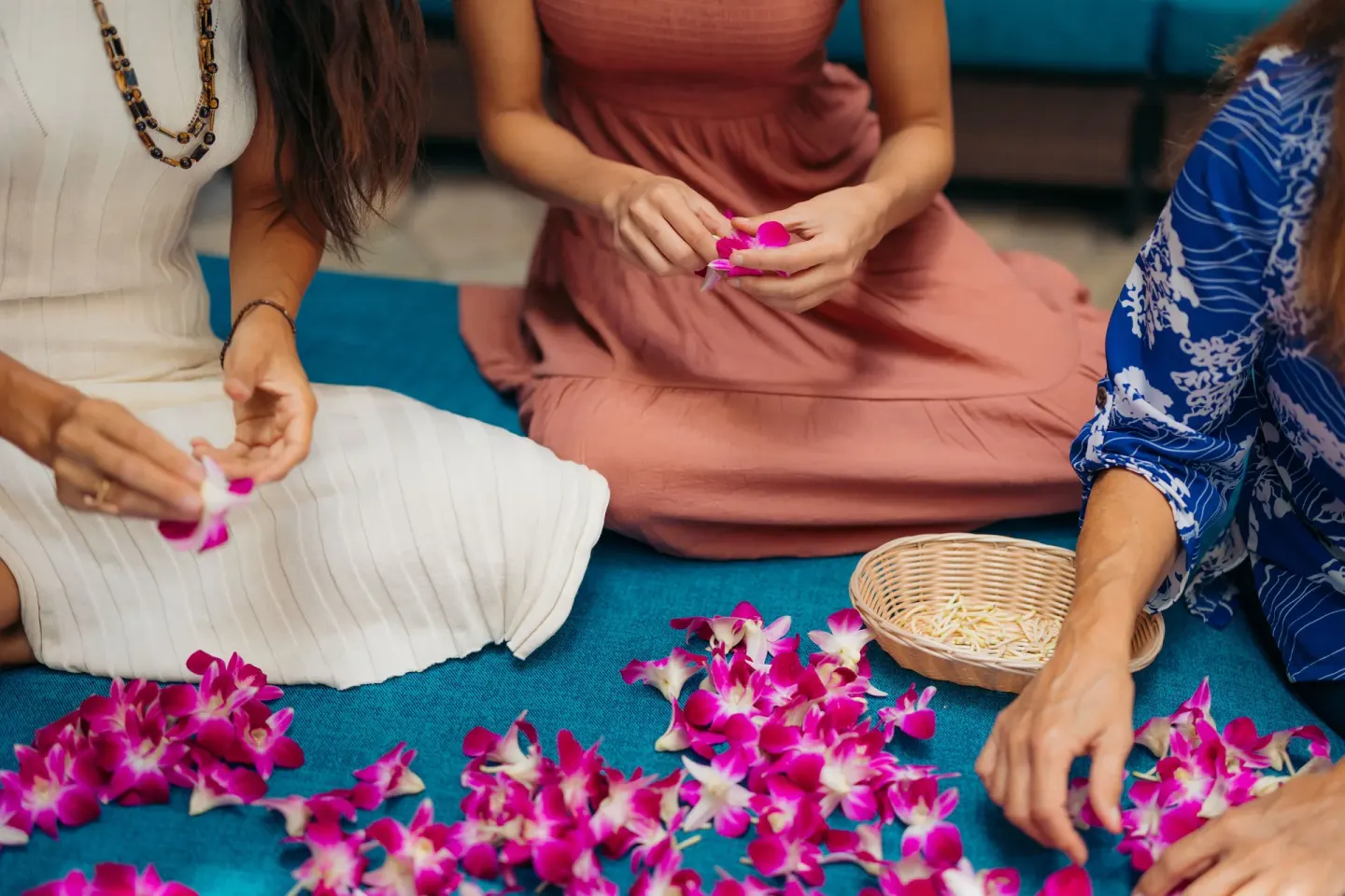 Guests arrange pink orchid blossoms on a blue lounge table at Waikiki Malia.
