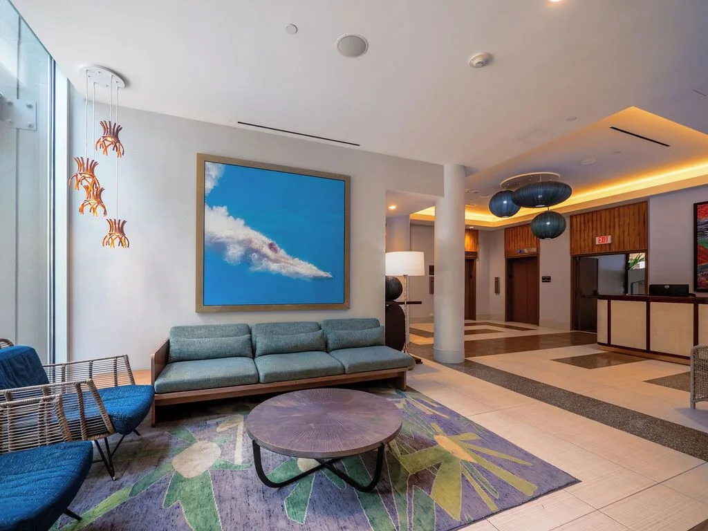Lobby lounge with sofa seating, artwork, and front desk beyond at Waikiki Malia.
