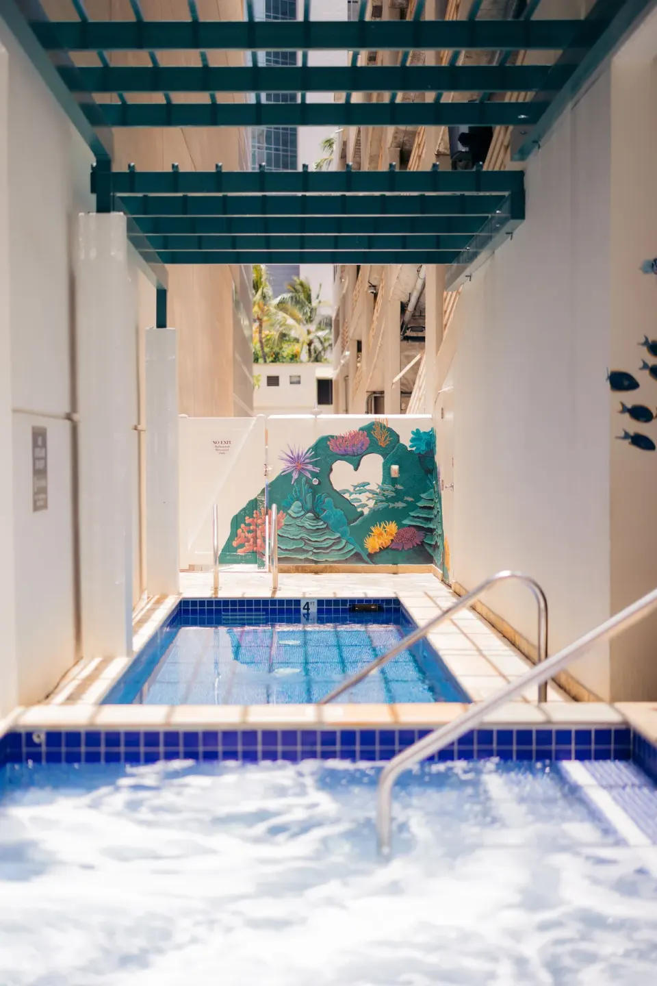 Outdoor pool and spa area with blue tile and mural at Waikiki Malia.