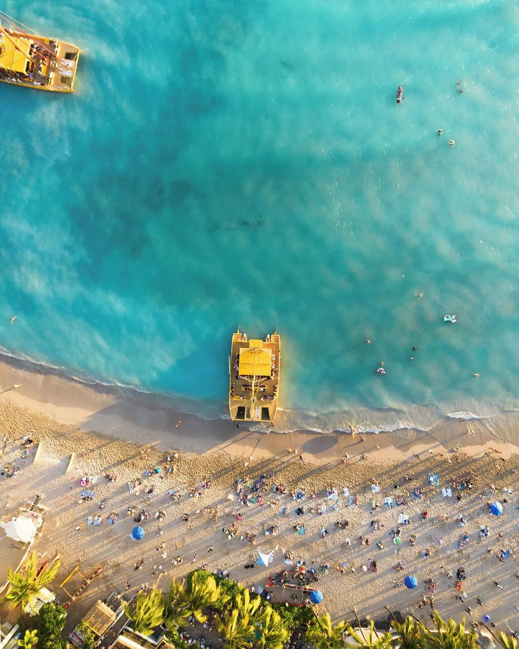 Aerial view of Waikiki Beach with turquoise water and catamarans, a short walk from Waikiki Malia.