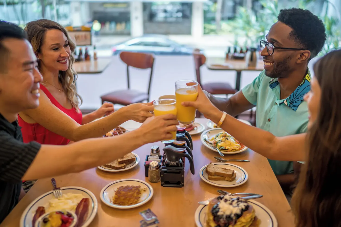 Friends toast with orange juice over breakfast at IHOP at Waikiki Malia.