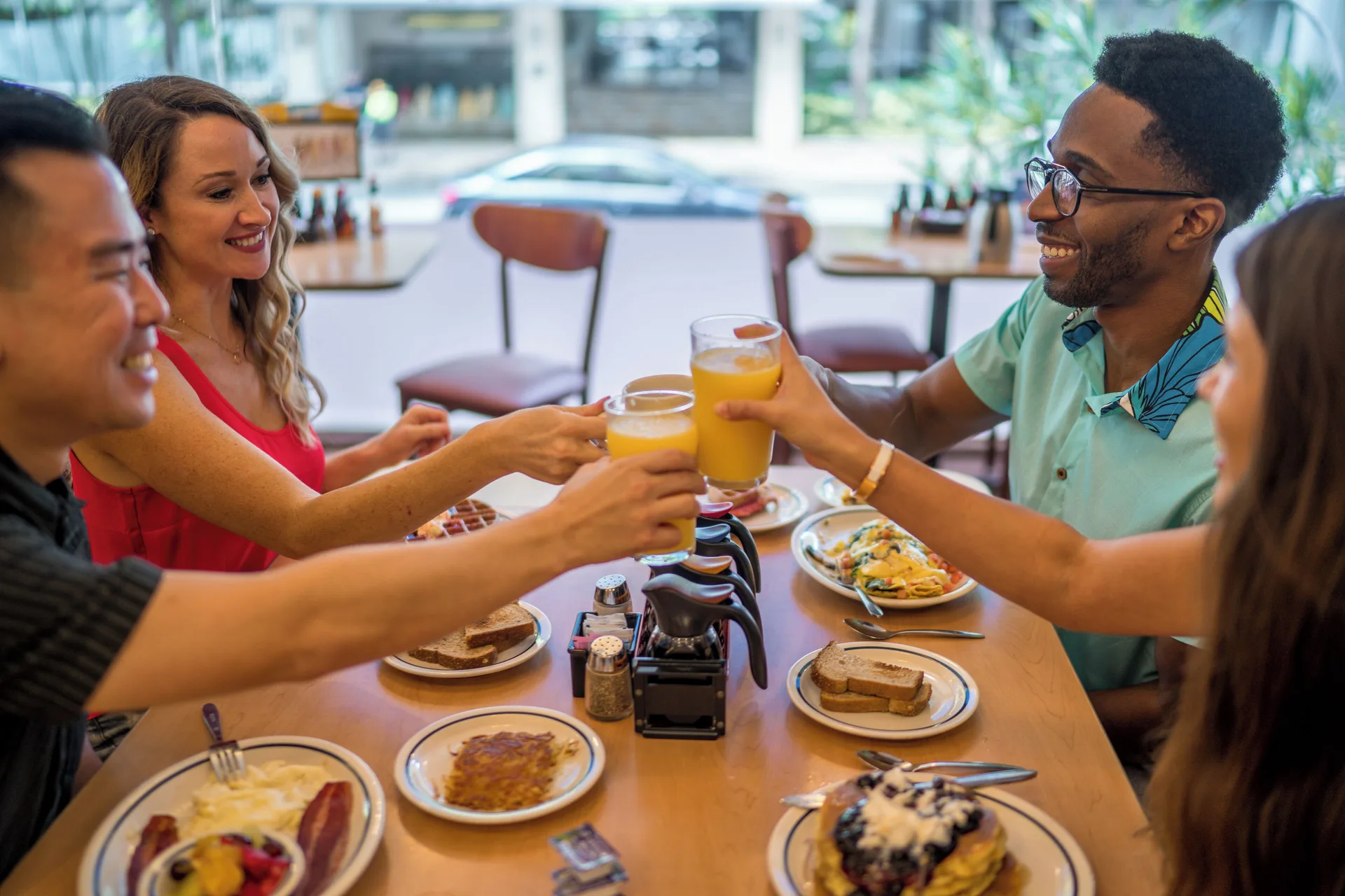 Friends toast with orange juice over breakfast at IHOP at Waikiki Malia.