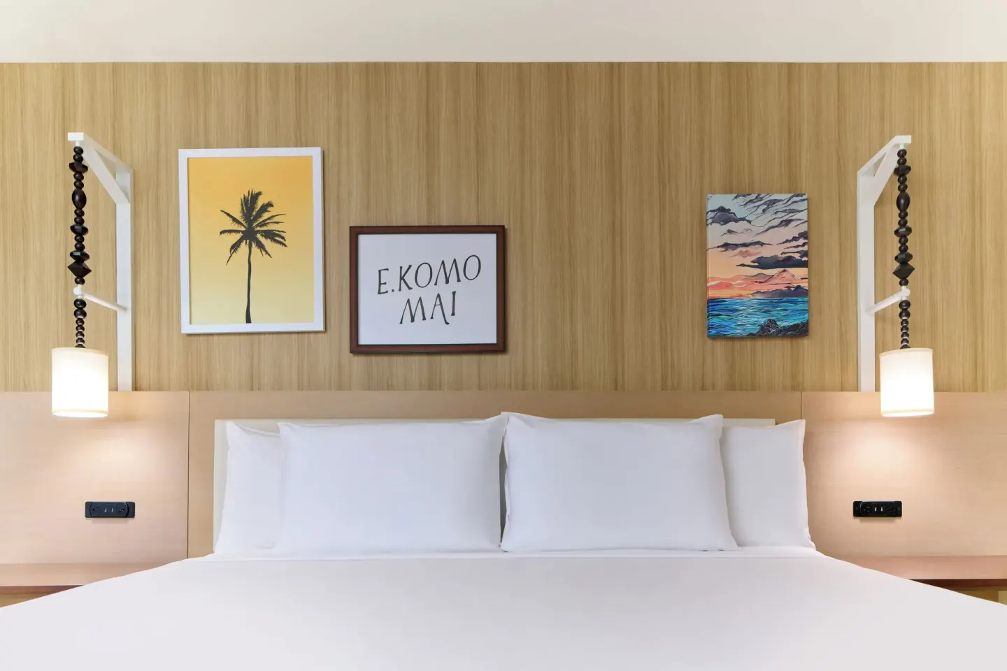 King bed with pendant lights and tropical wall art in a City View room at Waikiki Malia.