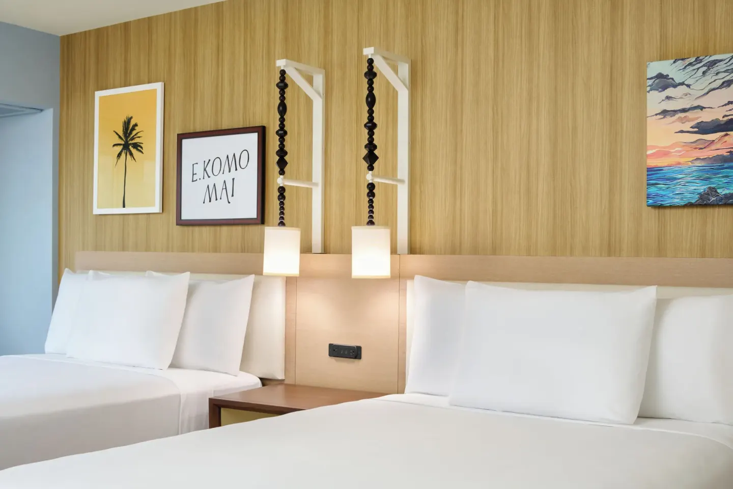 Two white beds with wall art and pendant lights in a City View room at Waikiki Malia.