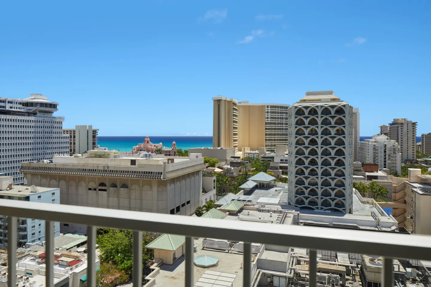 Partial ocean view from a Waikiki Malia balcony over Waikiki buildings.