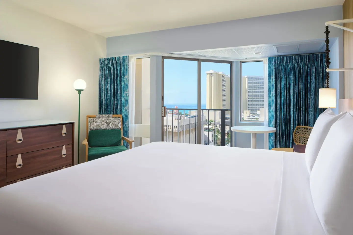 Partial Ocean View room with bed facing balcony and ocean glimpse at Waikiki Malia.