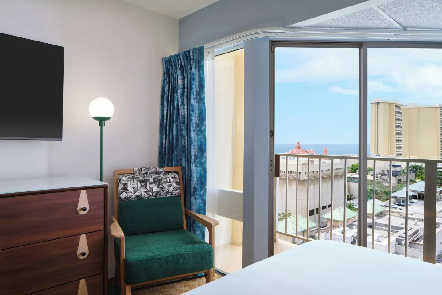 Partial Ocean View room seating by balcony doors and ocean glimpse at Waikiki Malia.