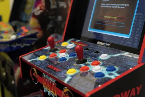 Colorful arcade controls and screens are shown in the game room at Waikiki Resort Hotel.