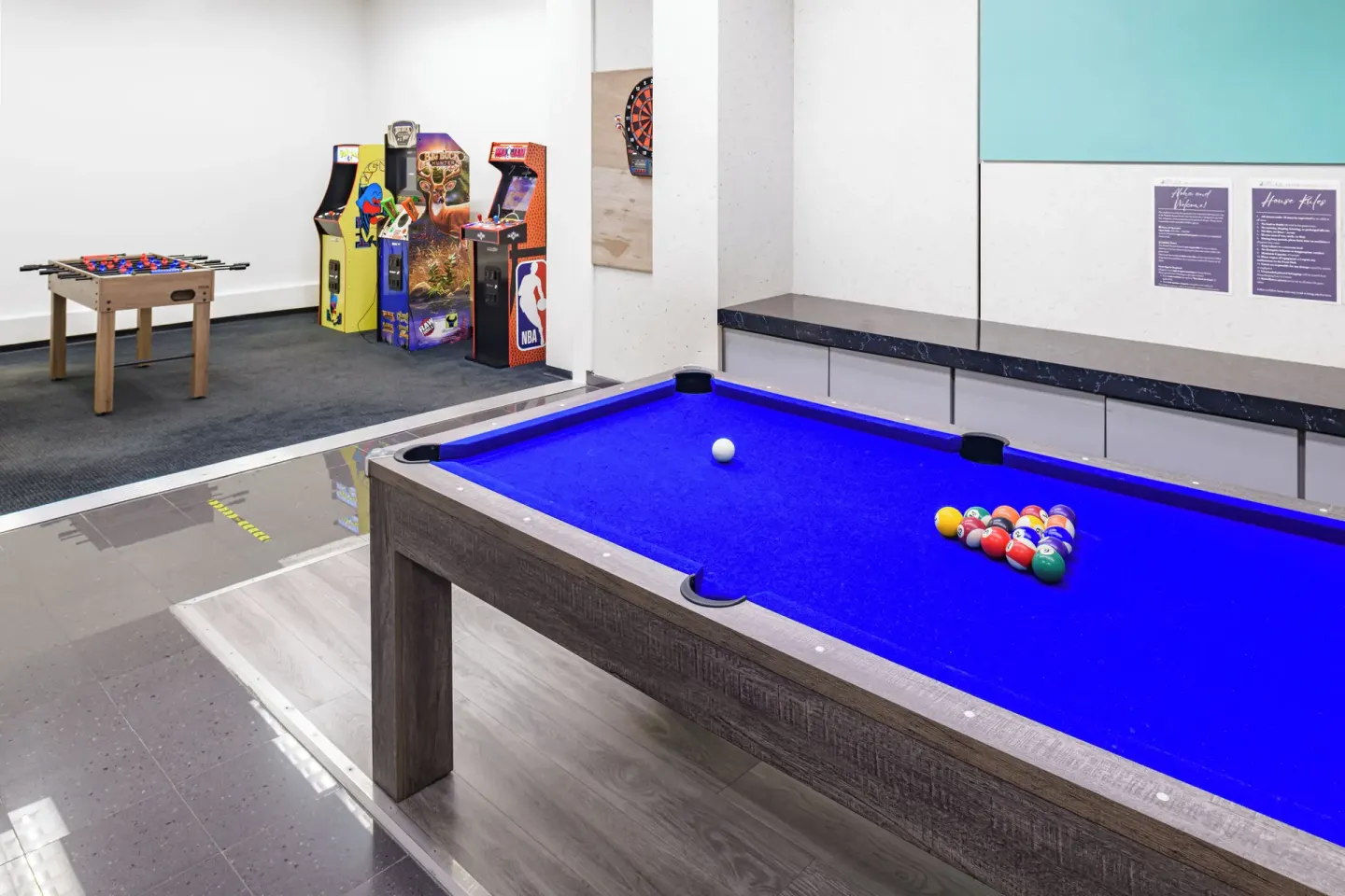 A pool table, foosball table, and arcade machines are shown in the game room at Waikiki Resort Hotel.