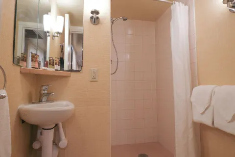 Compact guest bathroom with pedestal sink and curtained shower at Waikiki Resort Hotel.
