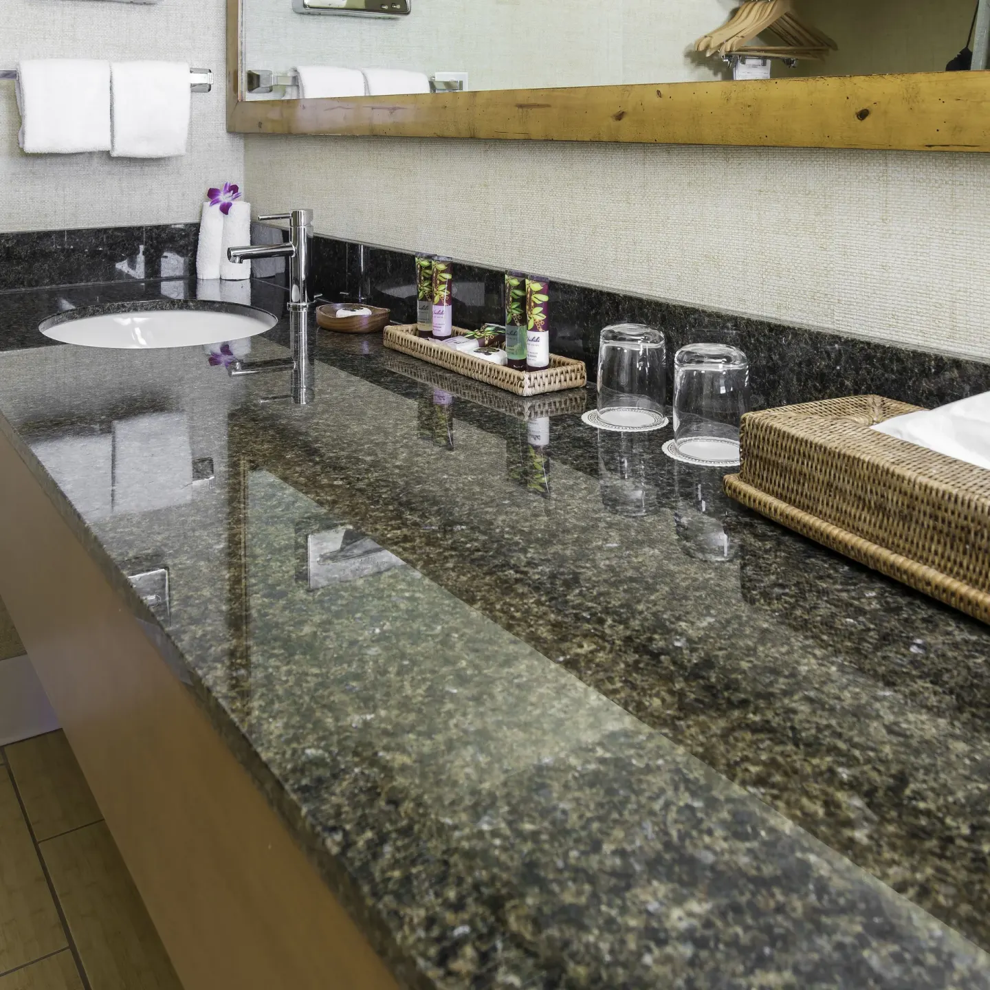 Guest bathroom vanity with granite counter, sink, glasses, and amenities at Waikiki Resort Hotel.