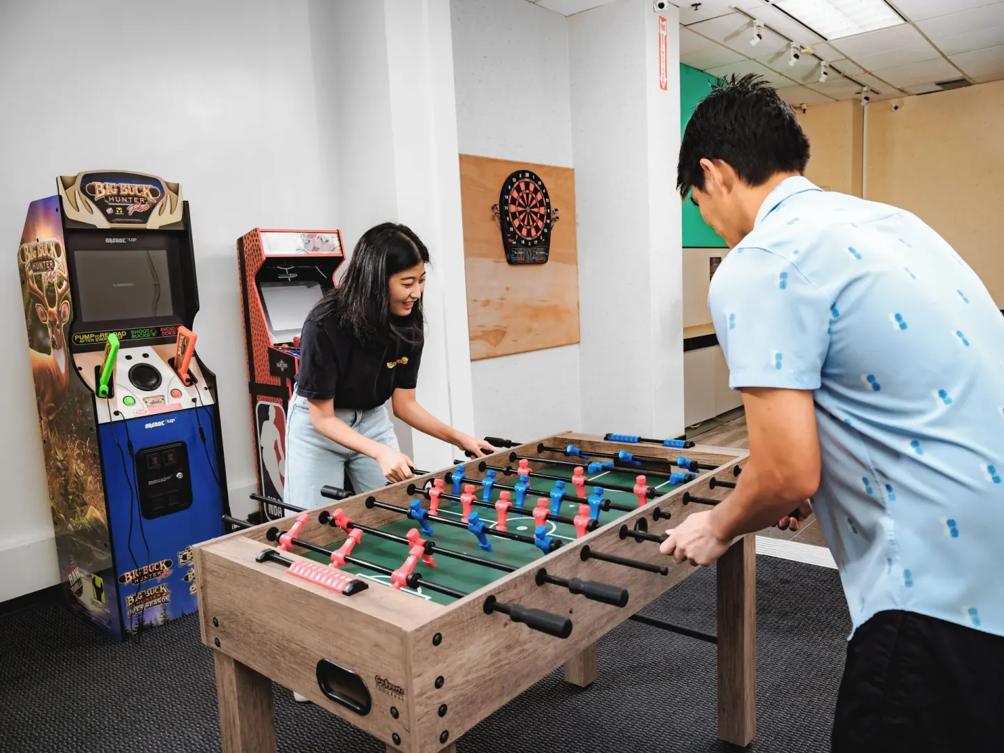Two guests play foosball beside arcade machines in the game room at Waikiki Resort Hotel.