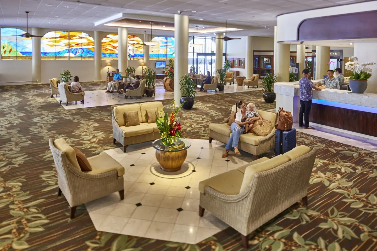 Busy lobby at Waikiki Resort Hotel with guests seated near the front desk and stained-glass windows.