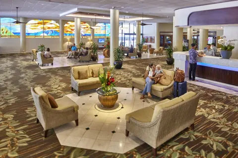 Busy lobby at Waikiki Resort Hotel with guests seated near the front desk and stained-glass windows.