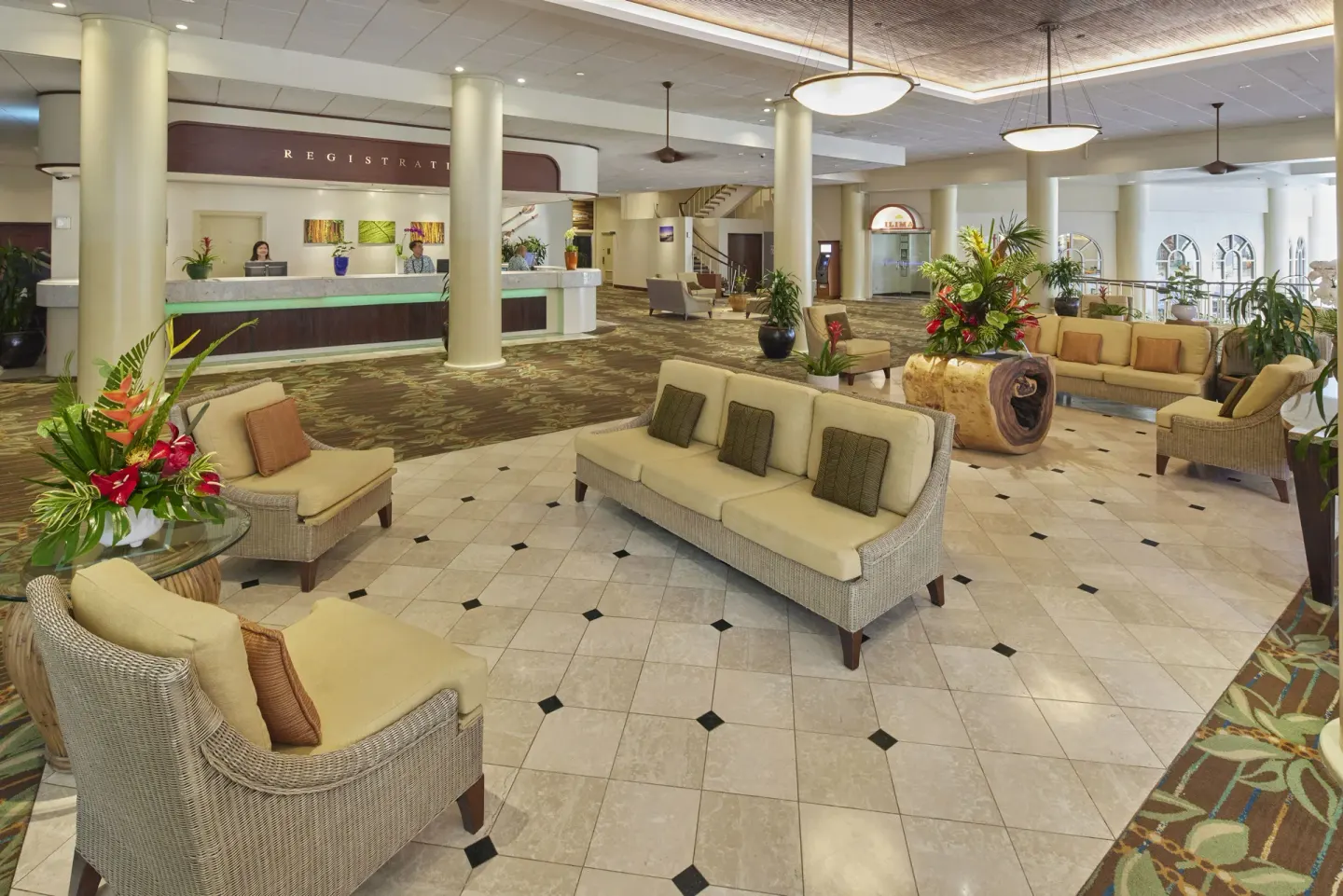 Lobby seating and registration desk at Waikiki Resort Hotel with tropical floral arrangements.