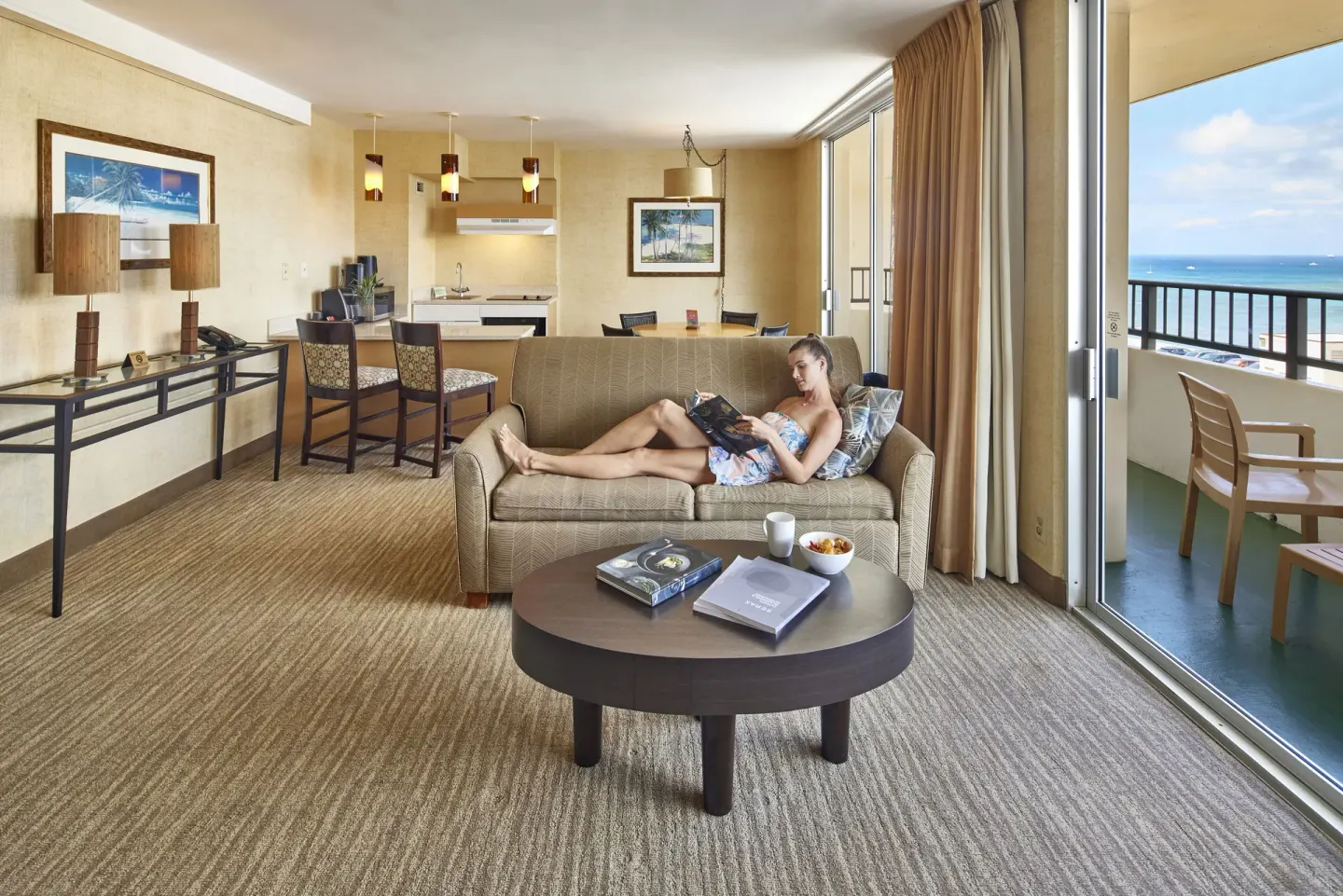 Suite living area with sofa, kitchenette, balcony, and ocean view at Waikiki Resort Hotel.