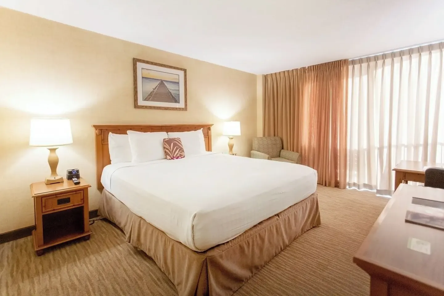 City View room with king bed, lamps, armchair, and curtained balcony at Waikiki Resort Hotel.