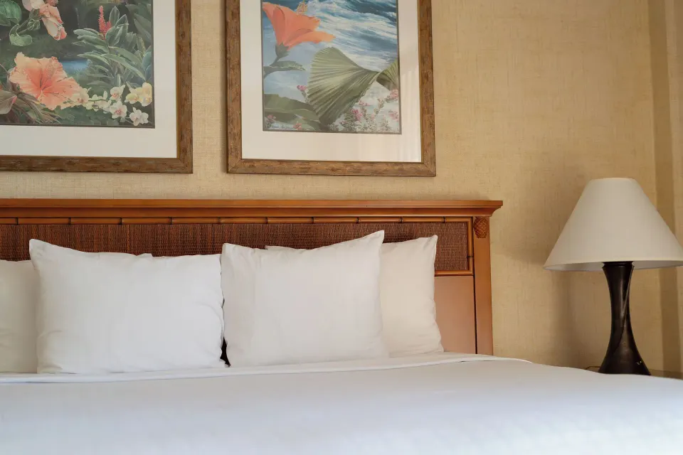 Close-up of a king bed with tropical artwork at Waikiki Resort Hotel.
