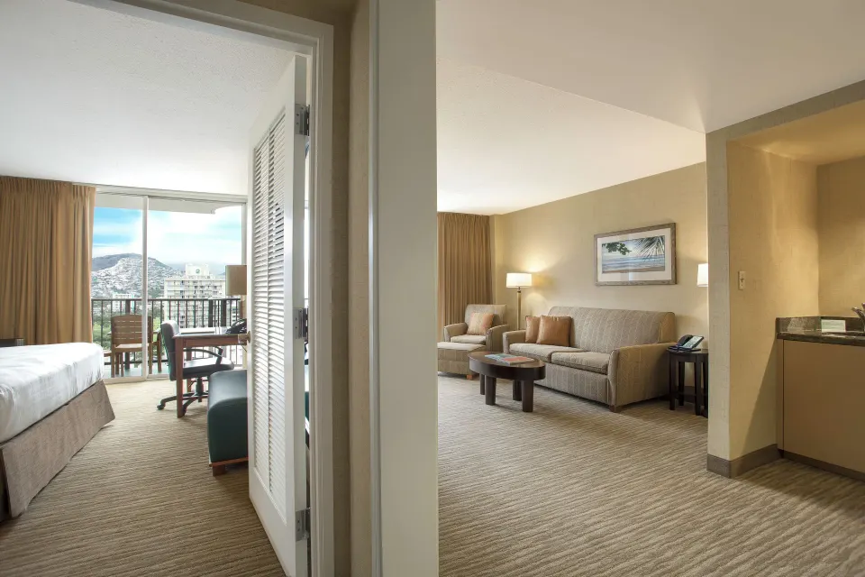 Suite Mountain View bedroom and living room at Waikiki Resort Hotel with balcony doors.