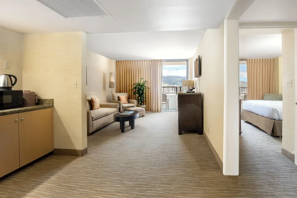 Suite Mountain View living area and bedroom at Waikiki Resort Hotel with balcony beyond.