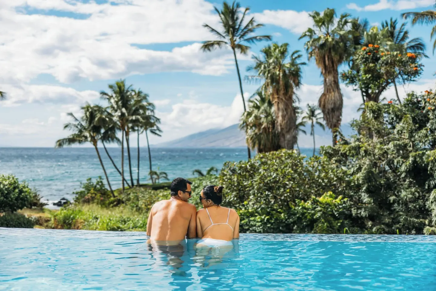 Couple in an infinity pool with ocean and palms at Wailea Beach Resort - Marriott, Maui.