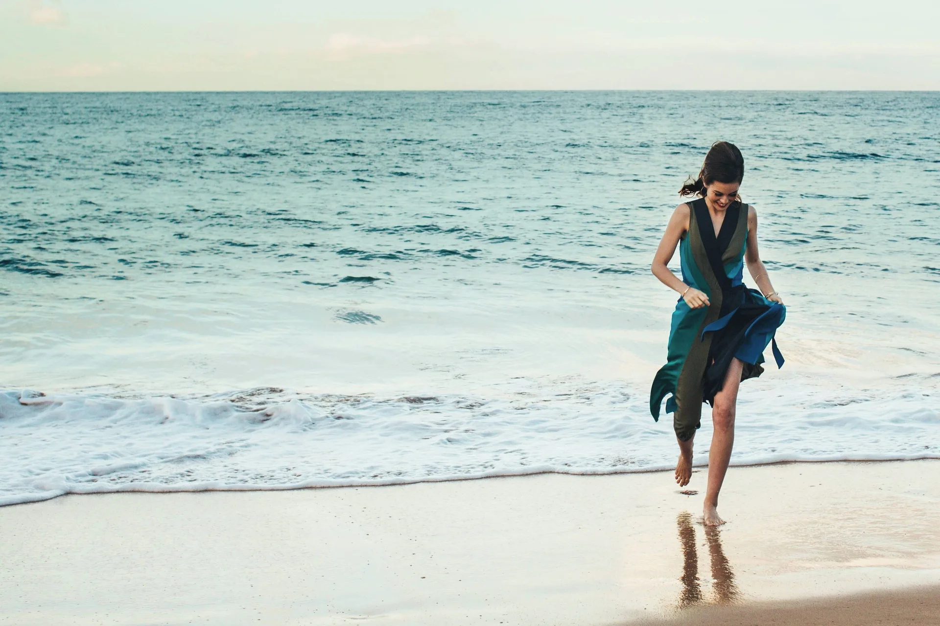 Woman walking at the waterline at Wailea Beach Resort - Marriott, Maui with ocean surf behind her.