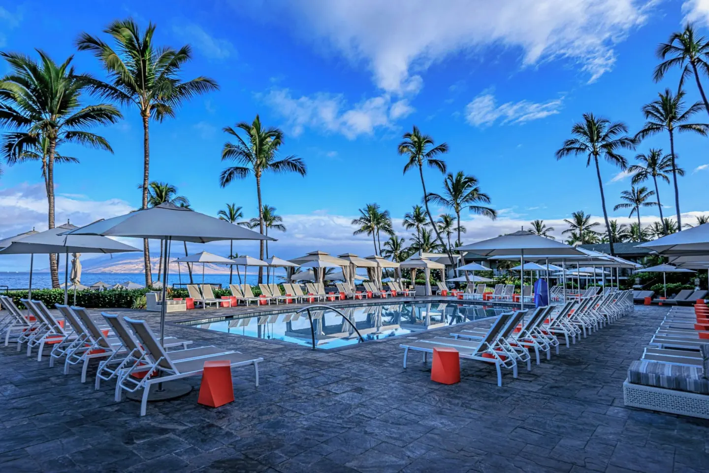 Resort pool deck with umbrellas, loungers, palms, and ocean at Wailea Beach Resort - Marriott, Maui.