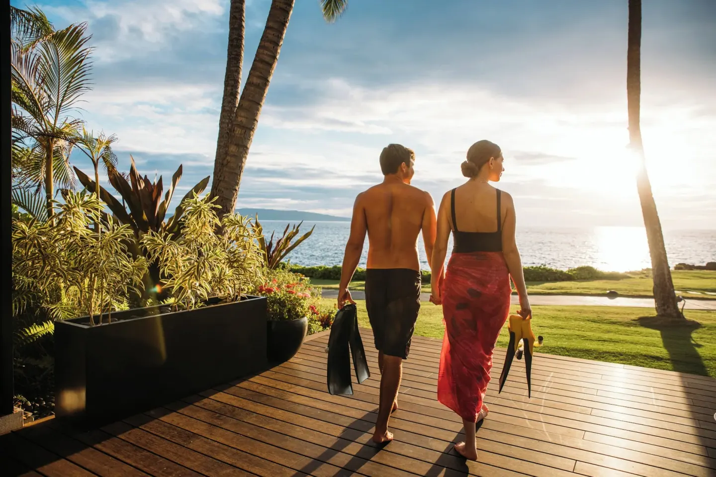 Couple carries swim fins toward the sunset ocean at Wailea Beach Resort - Marriott, Maui.