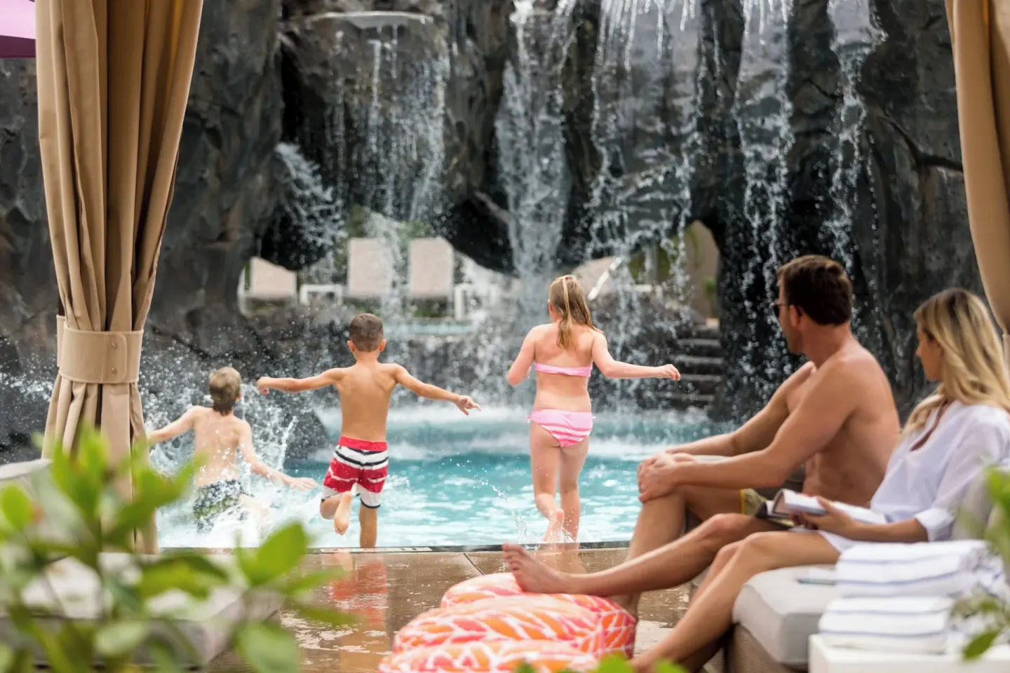 Children play by a waterfall pool while adults relax at Wailea Beach Resort - Marriott, Maui.