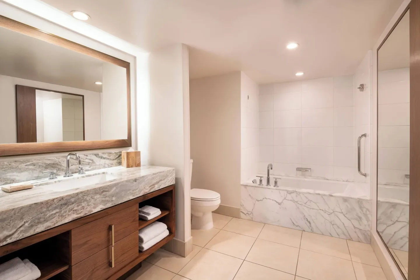 Oceanfront suite bathroom at Wailea Beach Resort - Marriott, Maui with marble vanity, tub and glass shower.