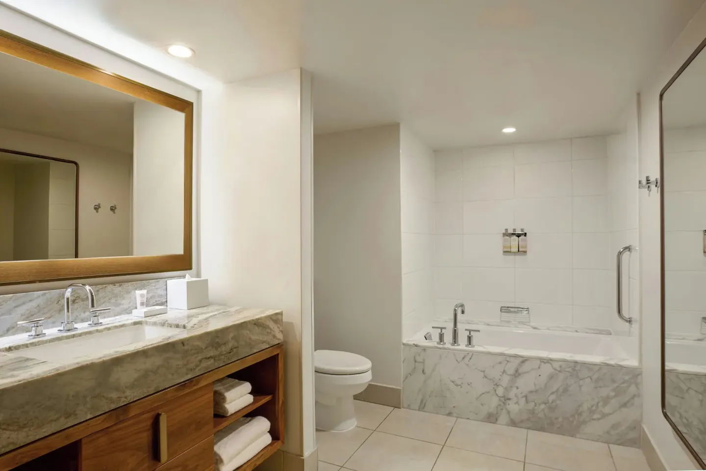 Suite bathroom at Wailea Beach Resort - Marriott, Maui with vanity, tub, shower and wall-mounted amenities.