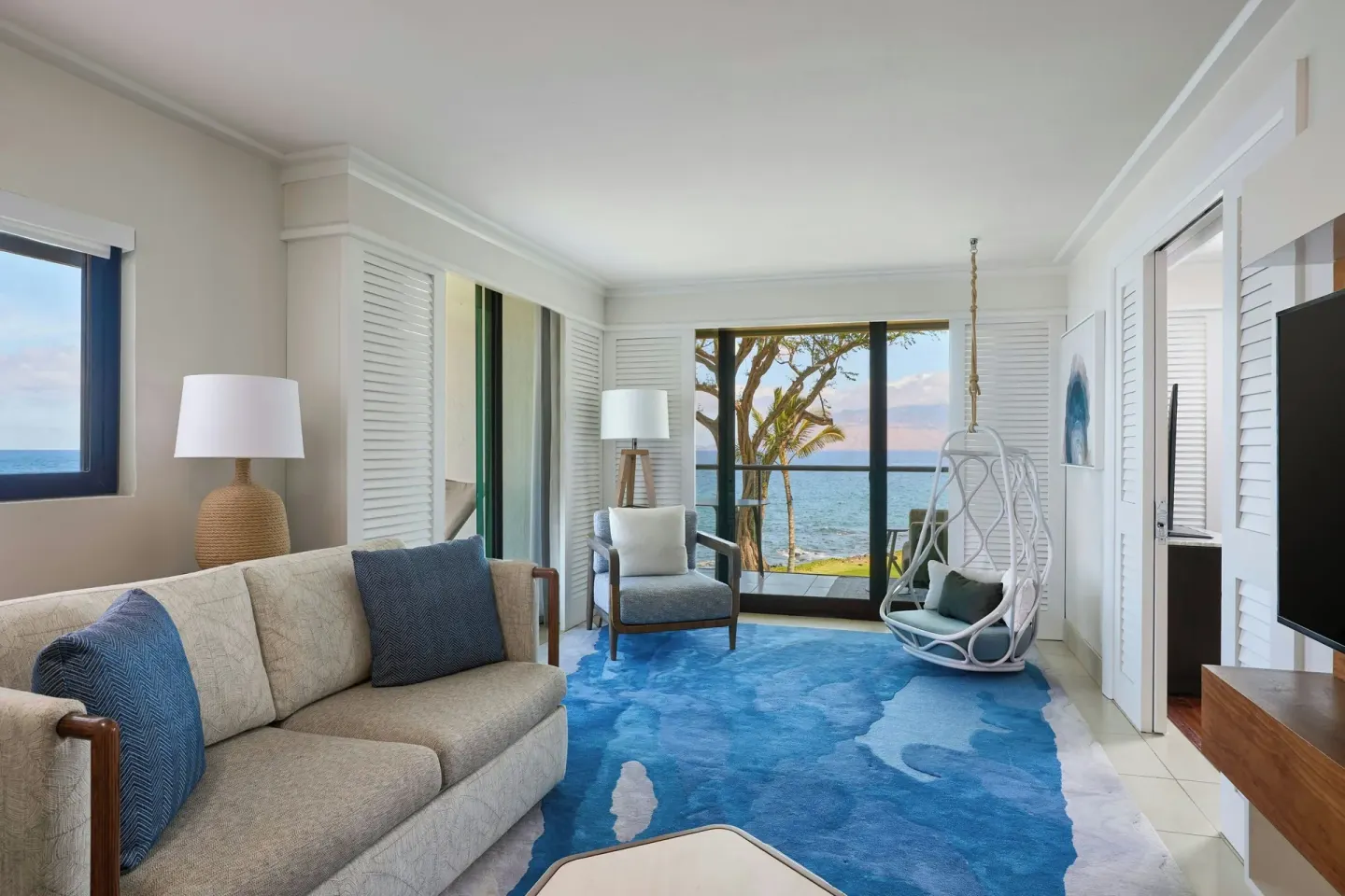 Oceanfront one-bedroom suite living room at Wailea Beach Resort - Marriott, Maui with sofa and hanging chair.
