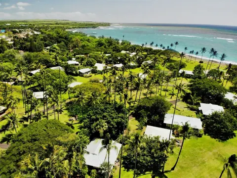 Aerial view of cottages, palms, lawns, and shoreline at Waimea Plantation Cottages.