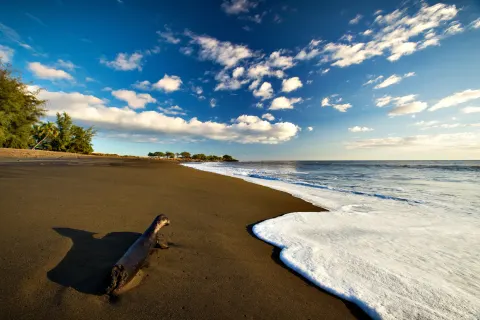 Black-sand beach and surf near Waimea Plantation Cottages.
