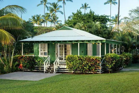Green plantation cottage with porch and tropical hedges at Waimea Plantation Cottages.