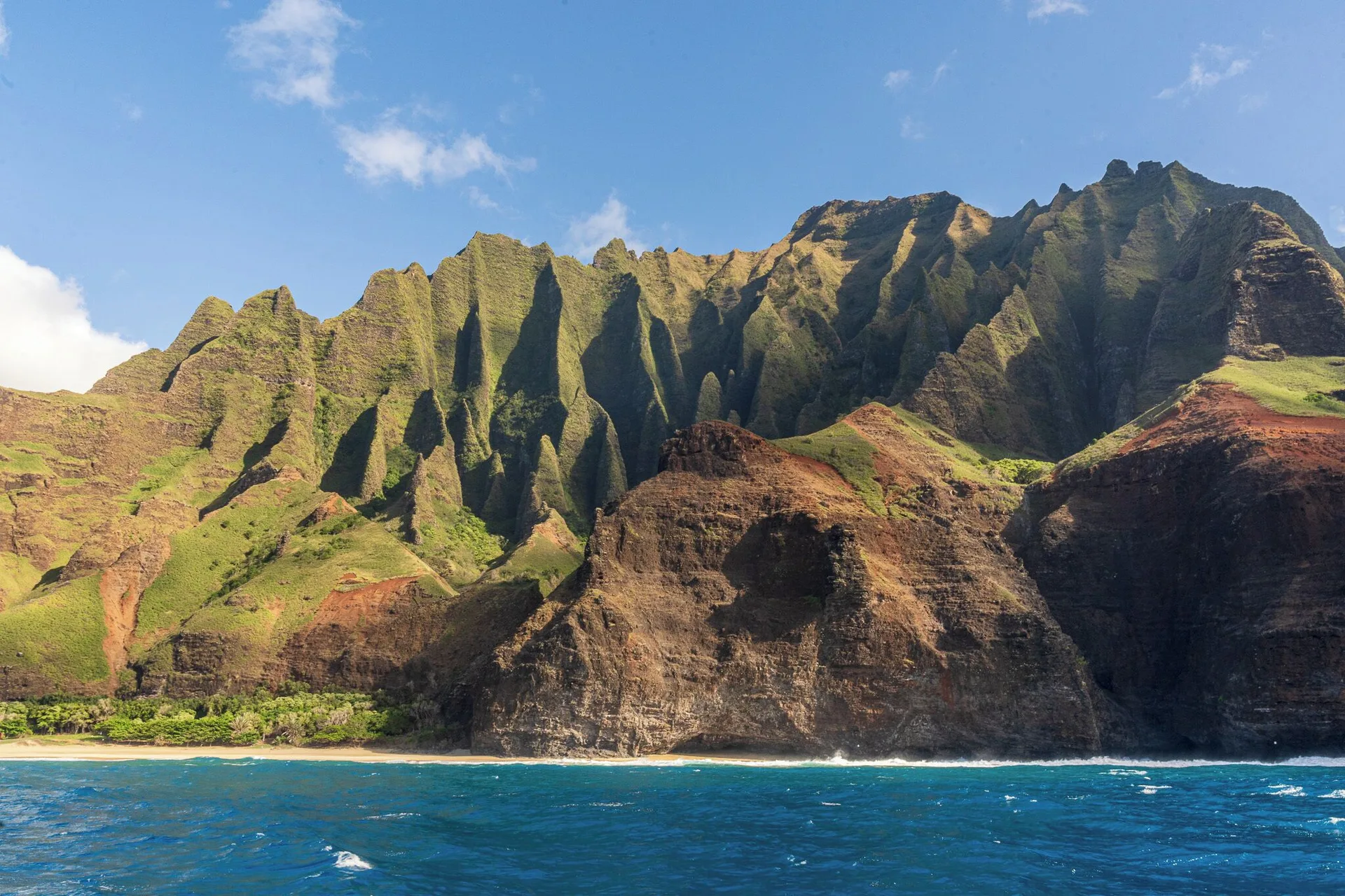 Green Kauai mountain cliffs above blue ocean near Waimea Plantation Cottages.