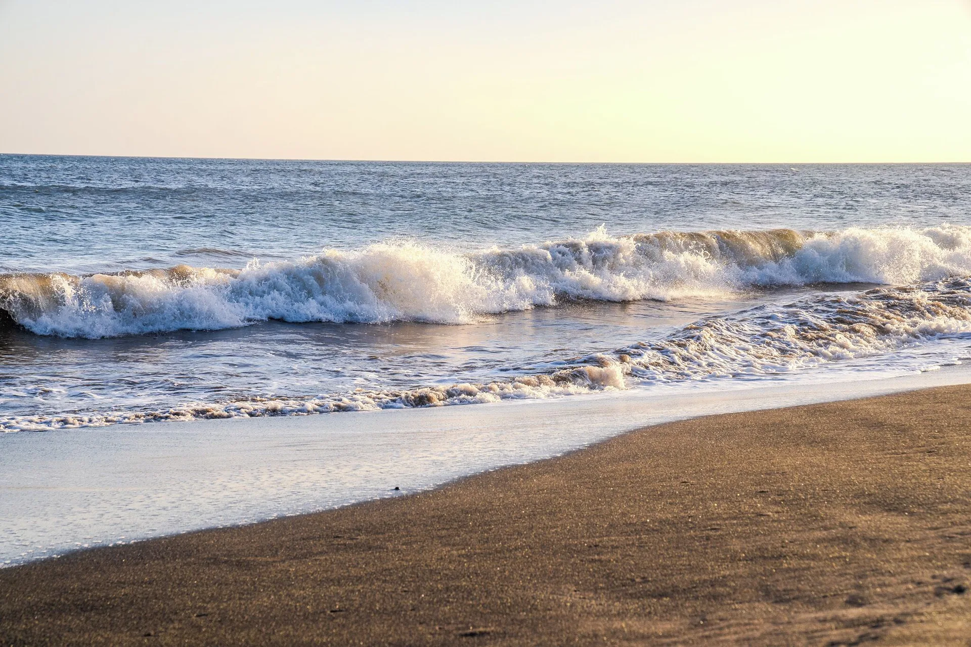Breaking waves on a sandy beach near Waimea Plantation Cottages.