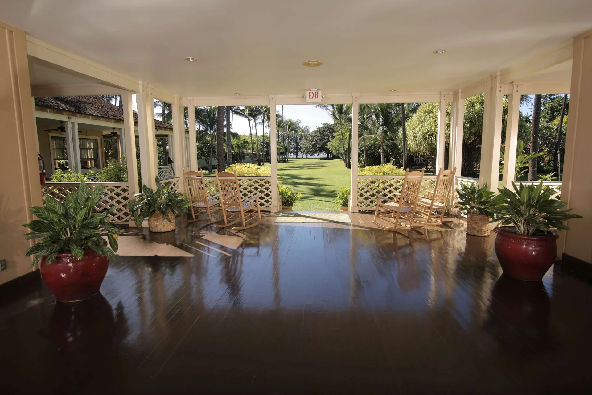 Open-air veranda with rocking chairs and garden views at Waimea Plantation Cottages.