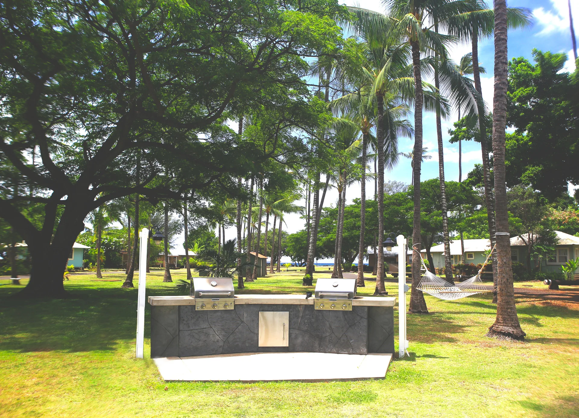Outdoor barbecue grills and a hammock on the lawn at Waimea Plantation Cottages.