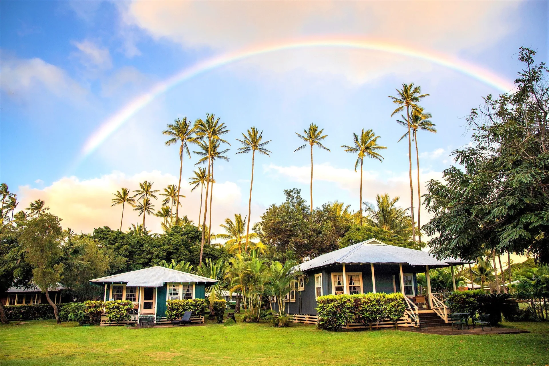 Rainbow over cottages and palm trees on the lawn at Waimea Plantation Cottages.