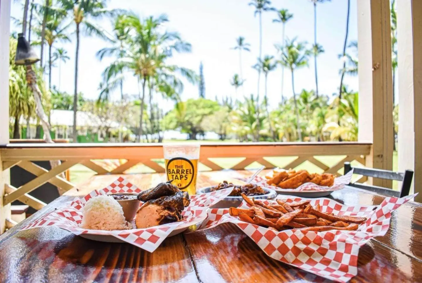 BBQ plates, fries, and a drink on a lanai table at Waimea Plantation Cottages.