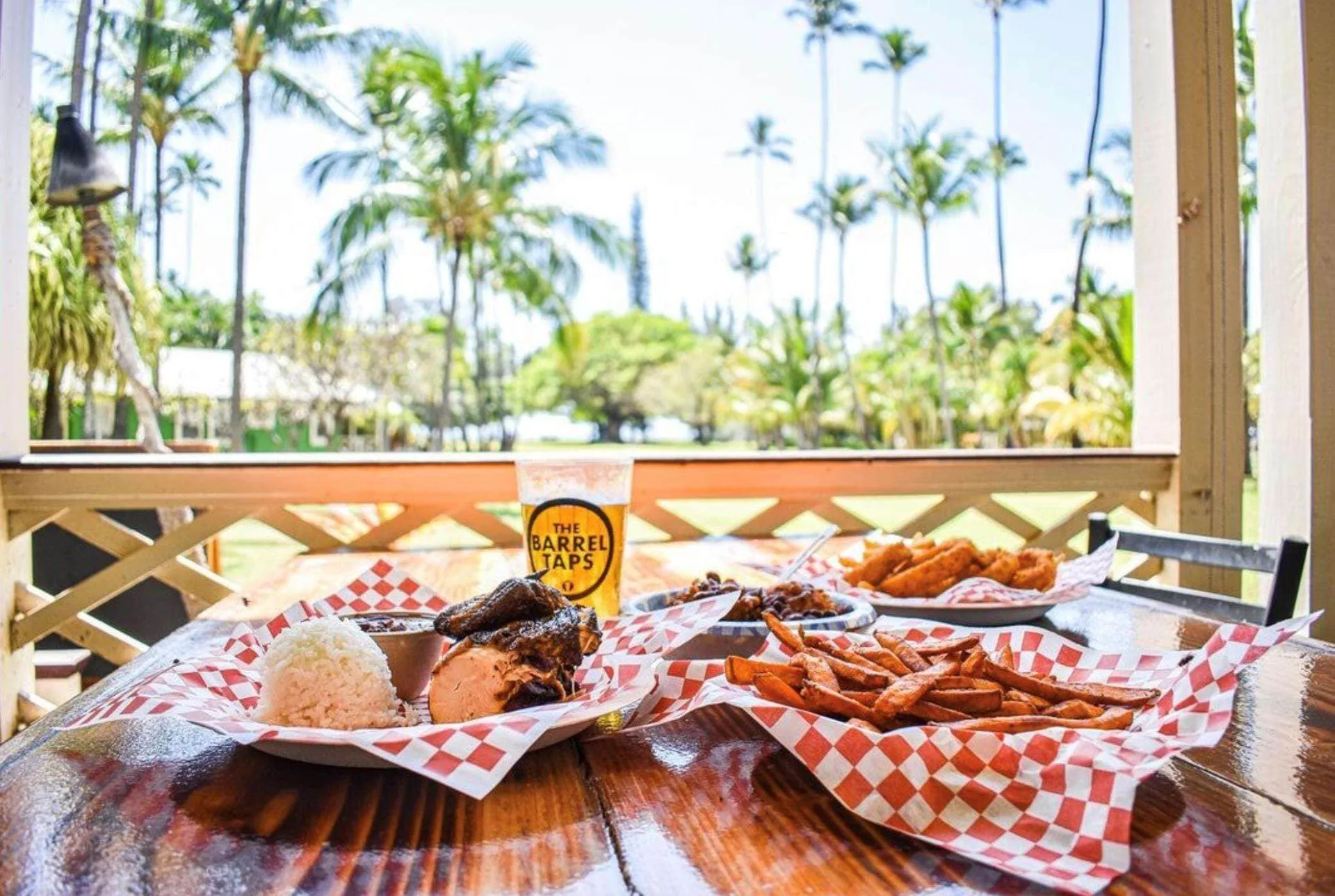 BBQ plates, fries, and a drink on a lanai table at Waimea Plantation Cottages.