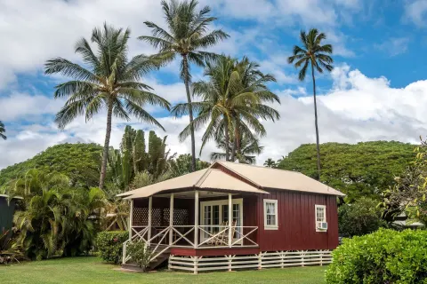 Coast Cottage exterior with porch and palms at Waimea Plantation Cottages.