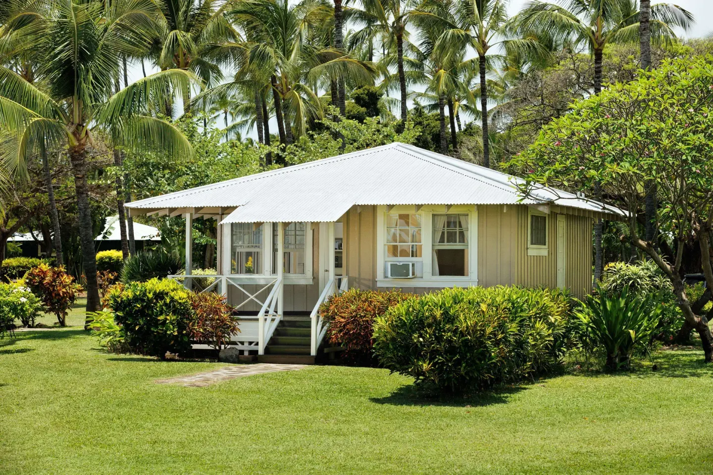 Coast Cottage One Bedroom Ocean View exterior at Waimea Plantation Cottages with palms and lawn.