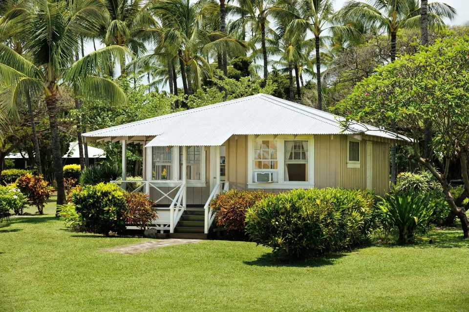 Coast Cottage One Bedroom Ocean View exterior at Waimea Plantation Cottages with palms and lawn.