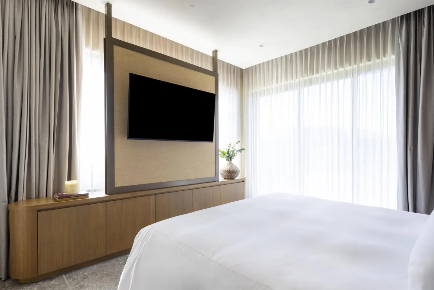Guest room bed facing a TV divider and bright windows at Waldorf Astoria Costa Rica Punta Cacique.