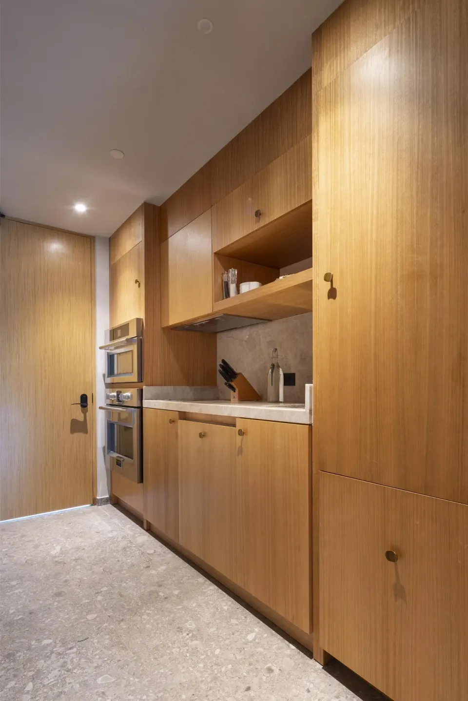 Guest room kitchenette with wood cabinetry and built-in appliances at Waldorf Astoria Costa Rica Punta Cacique.