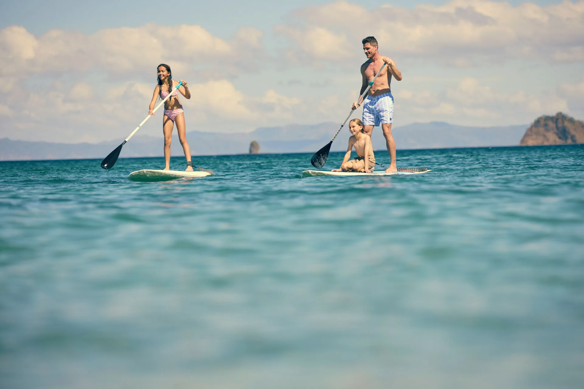 Guests paddleboarding on calm ocean water at Waldorf Astoria Costa Rica Punta Cacique.