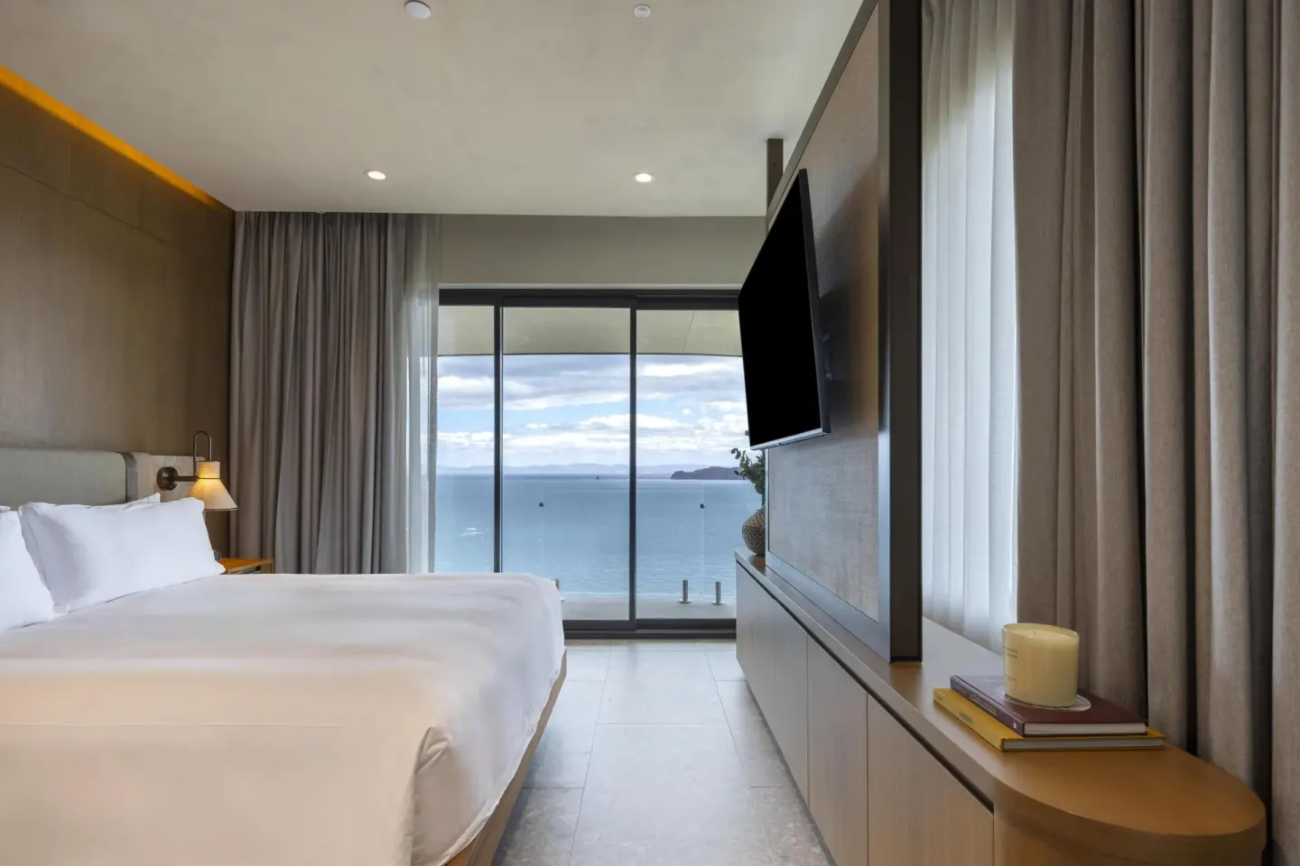 Guest room bed and television facing a balcony ocean view at Waldorf Astoria Costa Rica Punta Cacique.