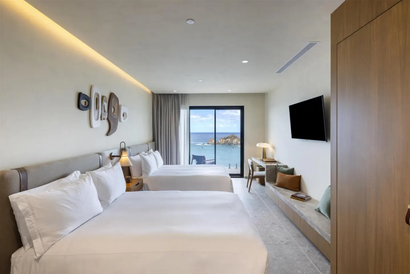 Two-bed ocean view guest room with desk and bench at Waldorf Astoria Costa Rica Punta Cacique.